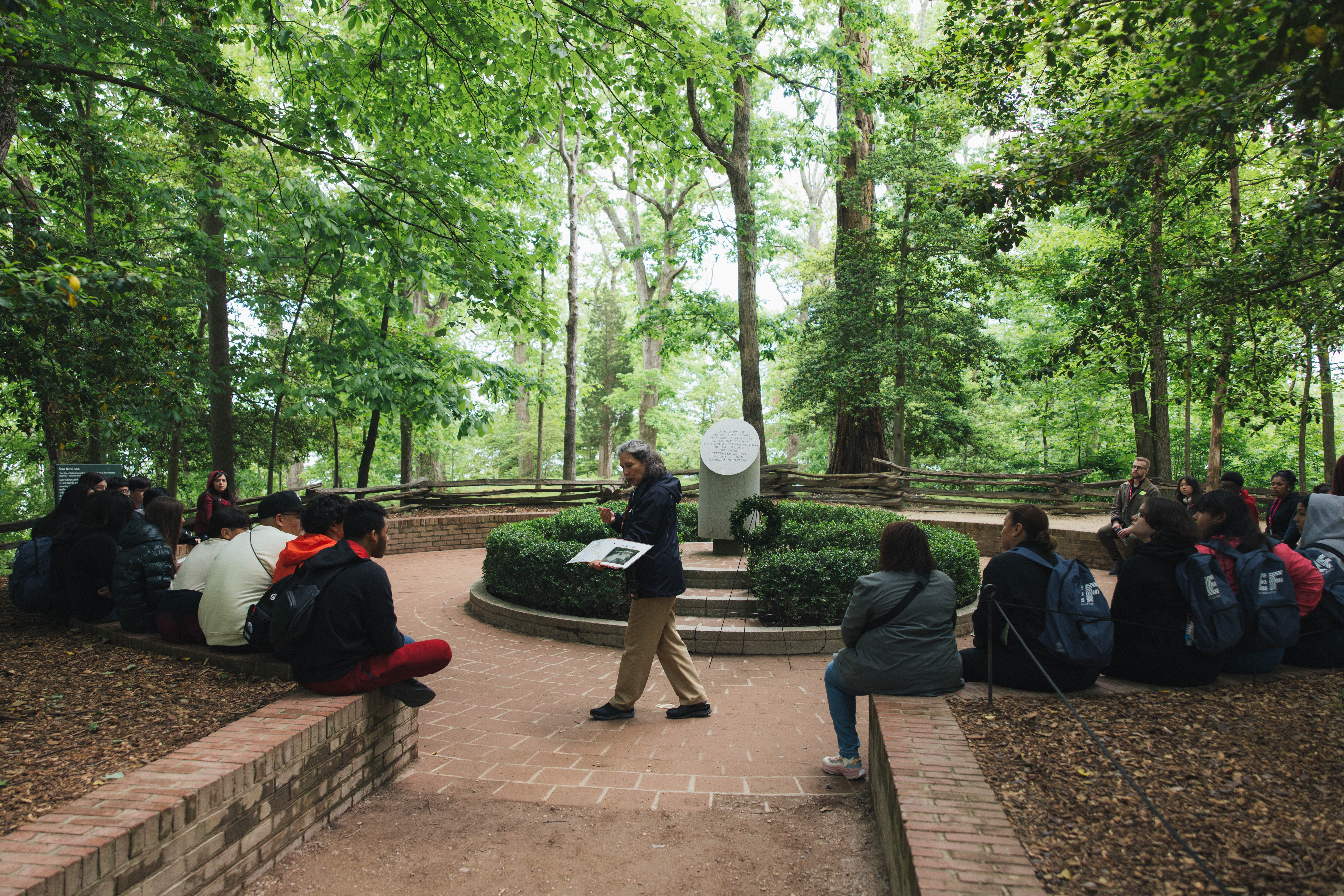 Inside Mount Vernon: Students gather around the Slave Memorial as a tour guide explains the significance of the monument.